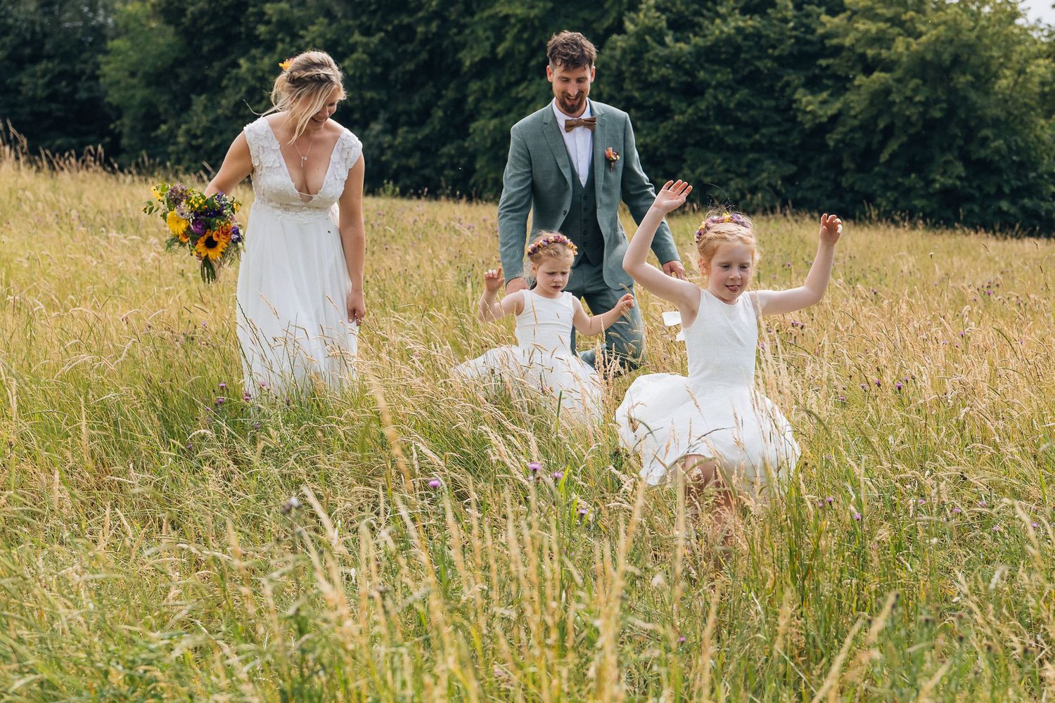 Family celebrating in a sunny meadow with tall grass and wildflowers.