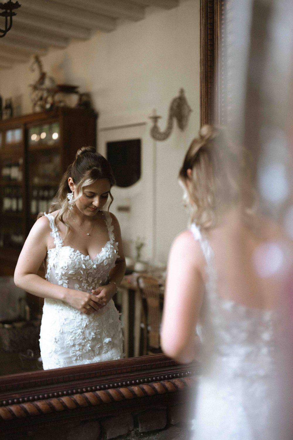 Bride admiring reflection in ornate mirror during wedding preparations.