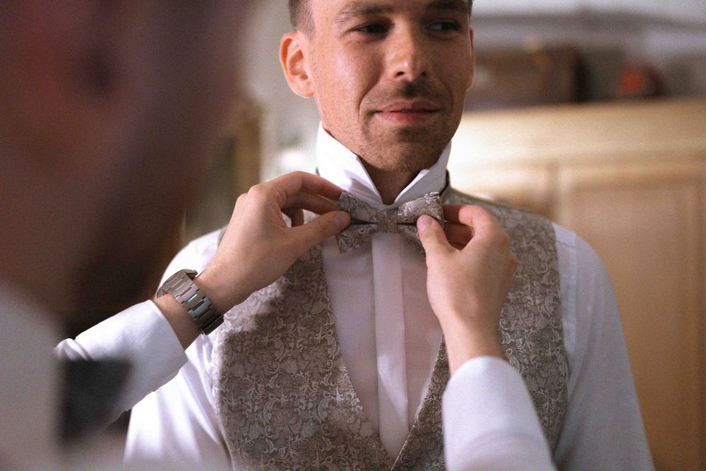 Groomsmen adjusting bow ties and formal attire before ceremony.