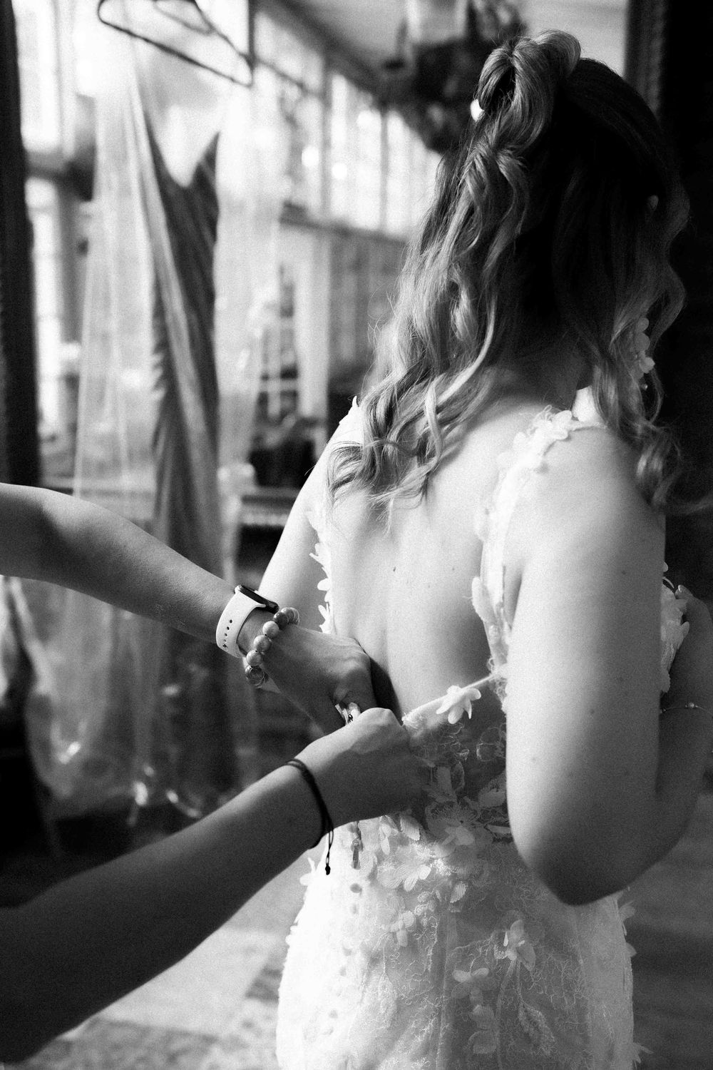 Black and white photo showing final wedding dress adjustments before ceremony.