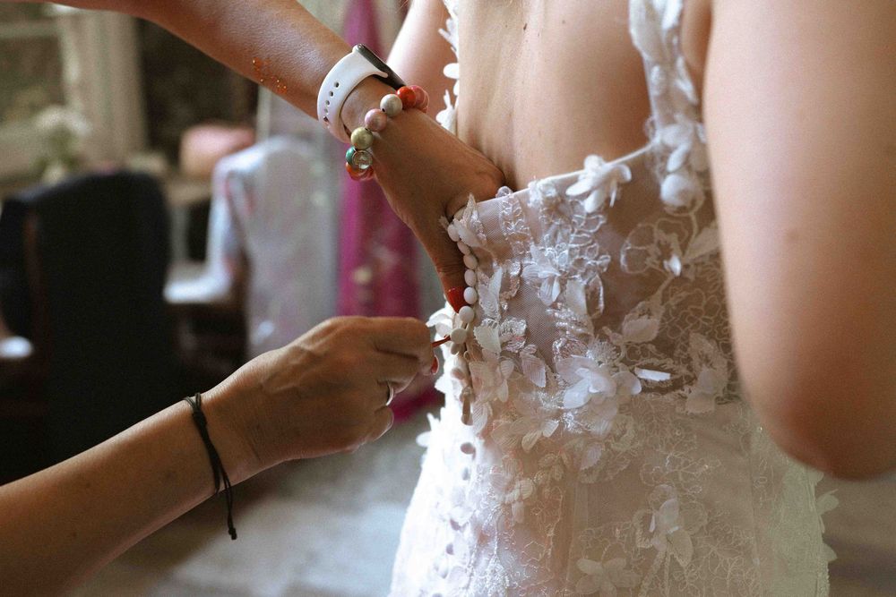 Close-up detail of hands adjusting a lace wedding dress.