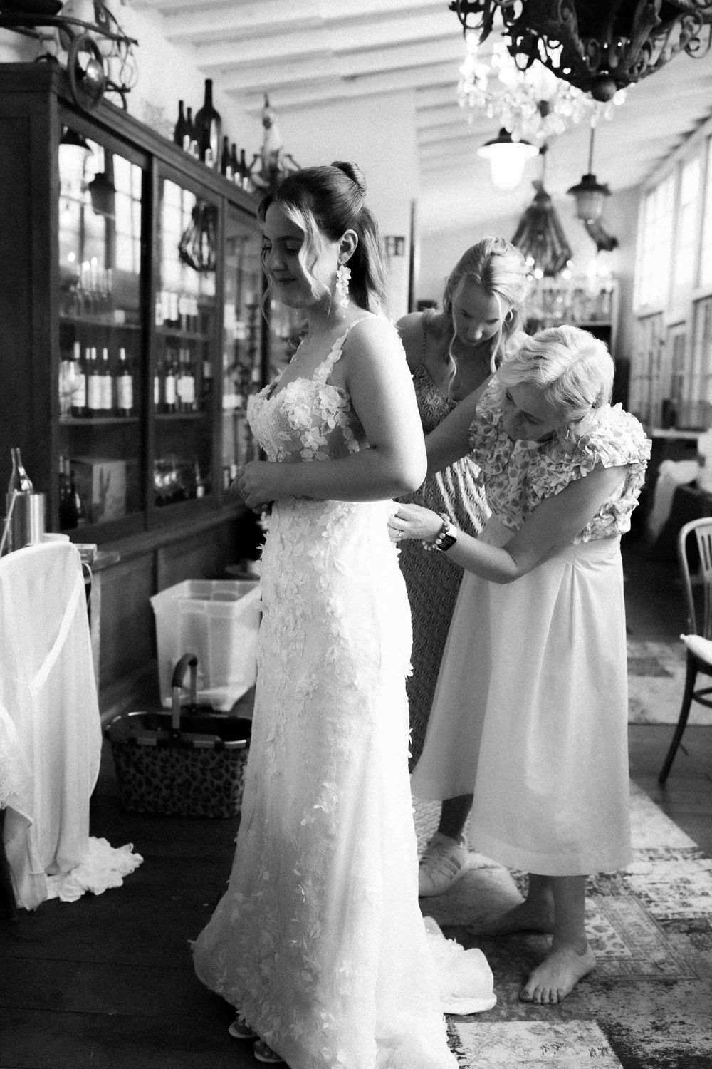 Black and white wedding preparation scene in vintage room with elegant chandelier lighting.