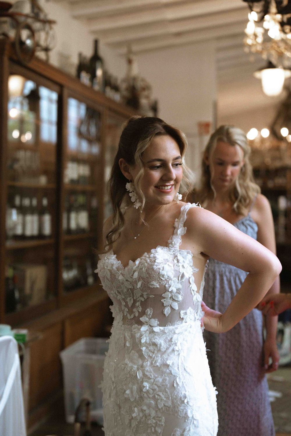 Elegant wedding dress fitting in rustic venue with delicate lace details and natural lighting.