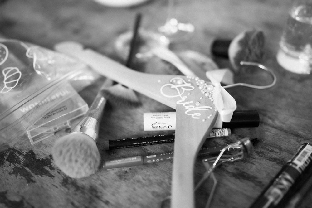 Close-up of beauty products and styling tools scattered on dark wooden surface.