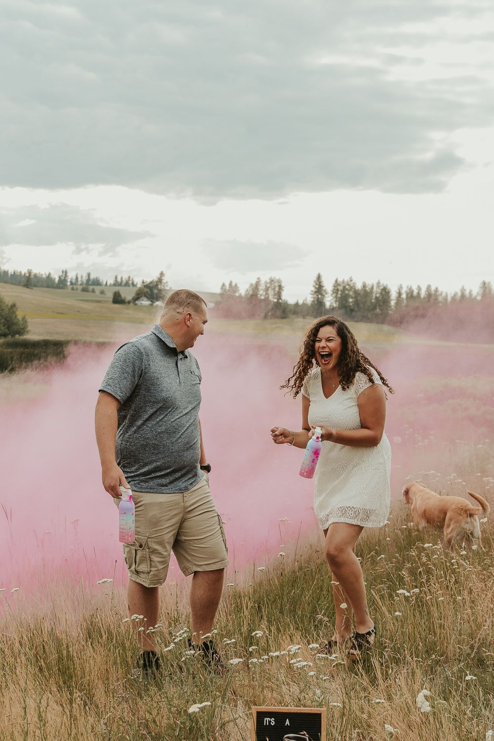 Celebrating gender reveal with pink powder smoke bombs in open field at outdoor photography venue in Spokane, Spokane family photographer