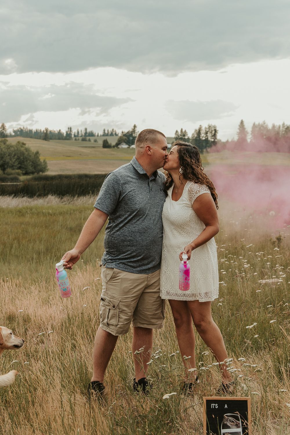 Celebrating gender reveal with pink powder smoke bombs in open field at outdoor photography venue in Spokane, Spokane family photographer