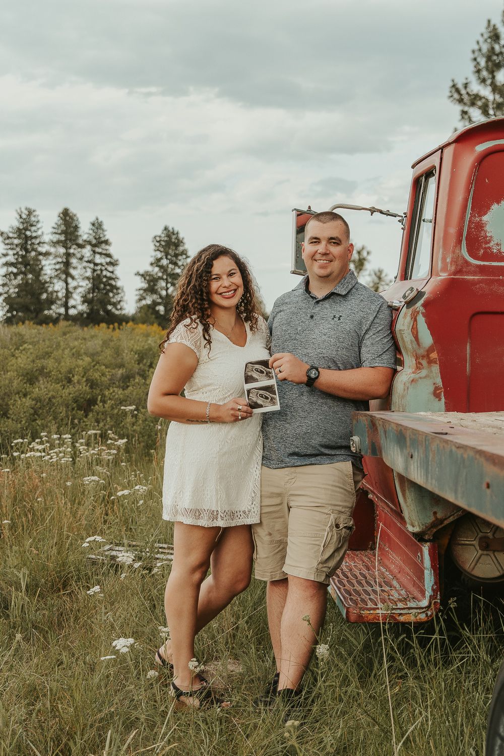 Celebrating gender reveal with pink powder smoke bombs in open field at outdoor photography venue in Spokane, Spokane family photographer