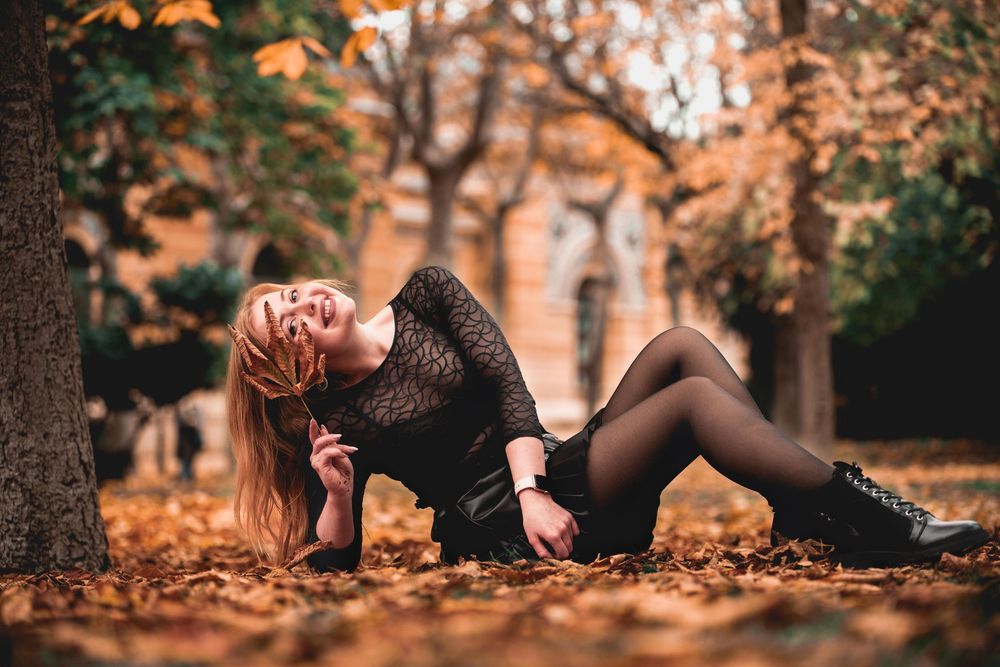 Artistic autumn photoshoot in a park with low angle views of people among fallen leaves.