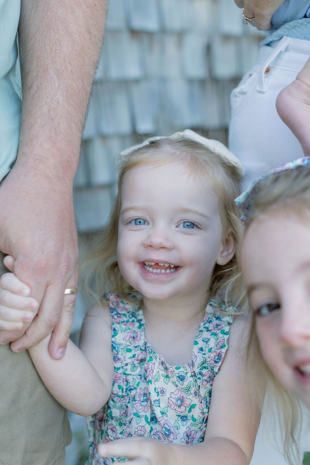 Family portrait with floral dress showing togetherness and smiles against a light blue background.