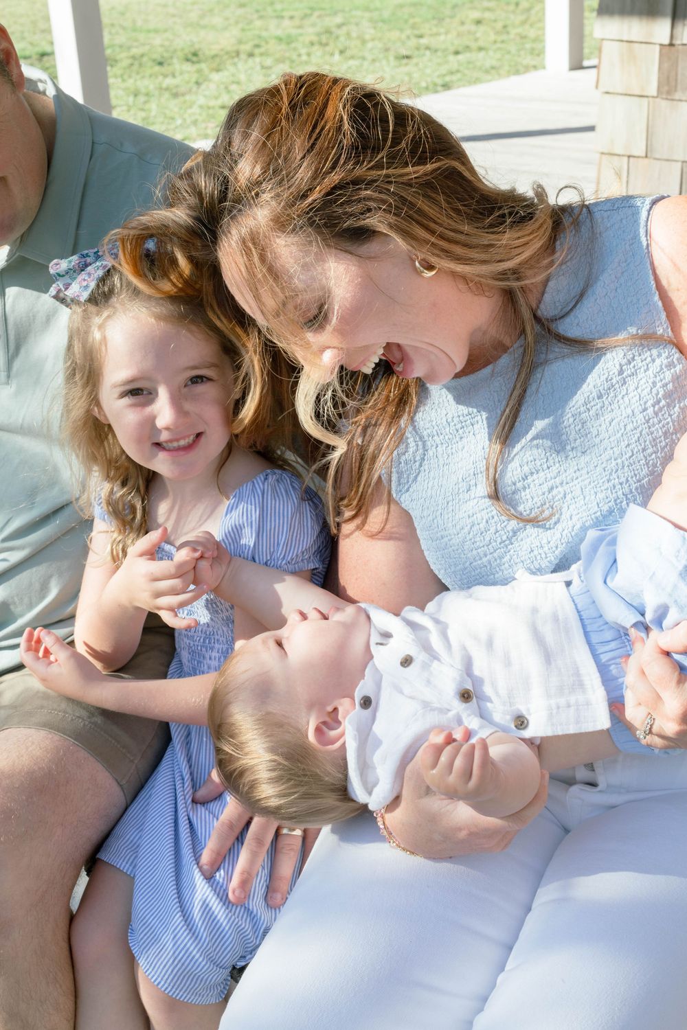 A candid family moment of tender affection and laughter while relaxing together on a porch.