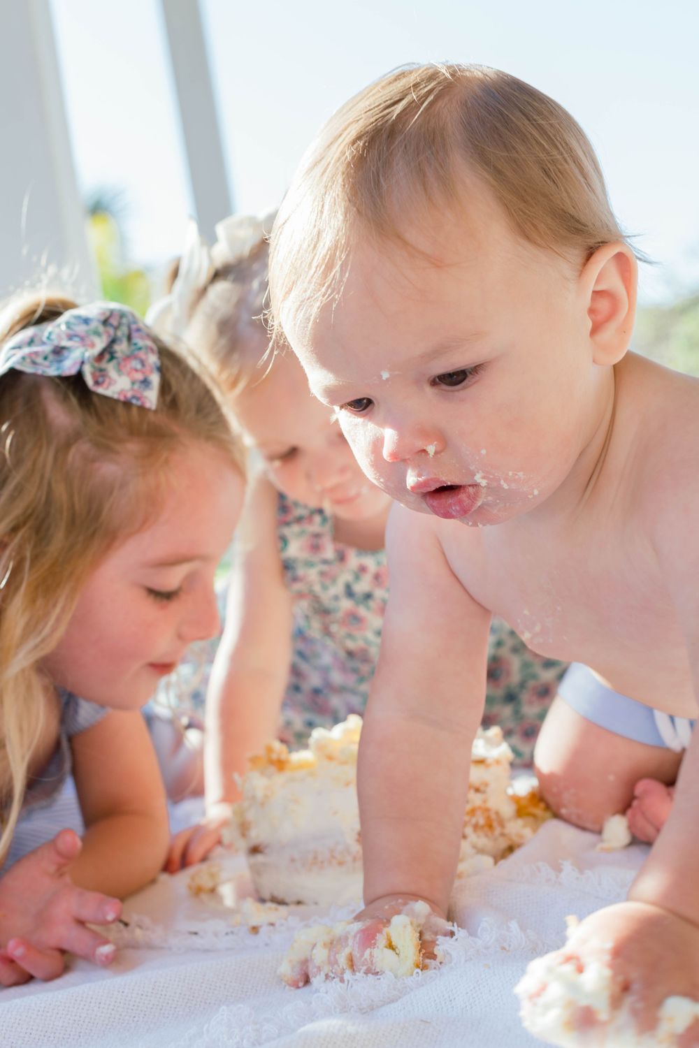 Children eagerly eating and tasting birthday cake directly from the table surface while bending down.