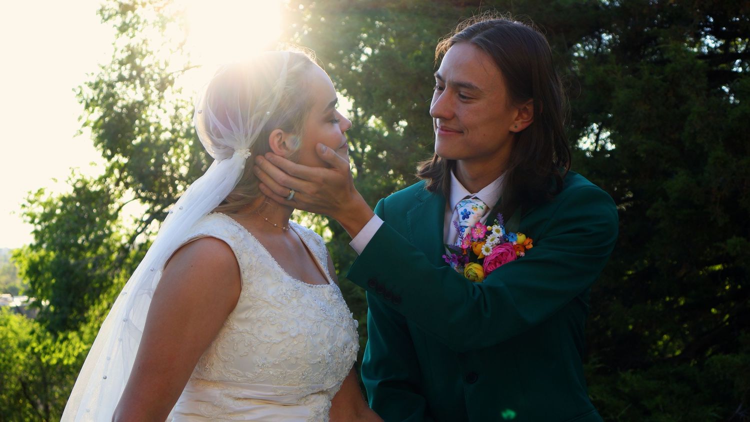 Newlywed couple sharing a romantic moment outside a LDS temple surrounded by lush green trees.