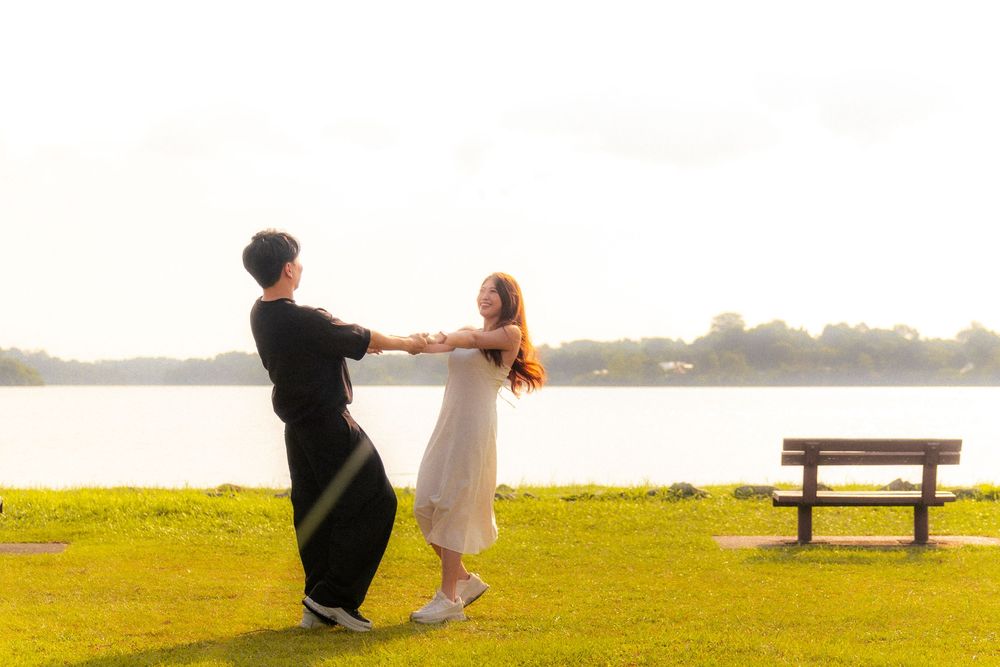 Two people share a romantic moment on a misty green hilltop with low visibility during sunset.