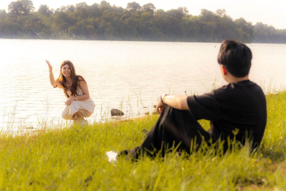 People spending leisure time by the tranquil lakeside on a sunny day.