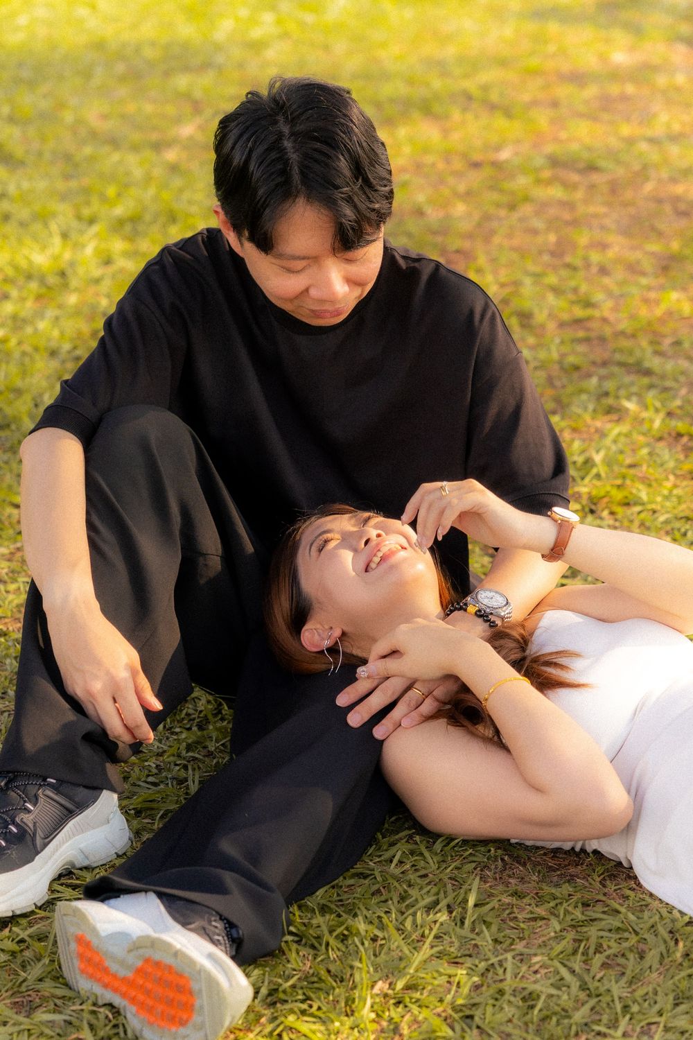 A couple lying on grass during a romantic sunset moment together in the park.