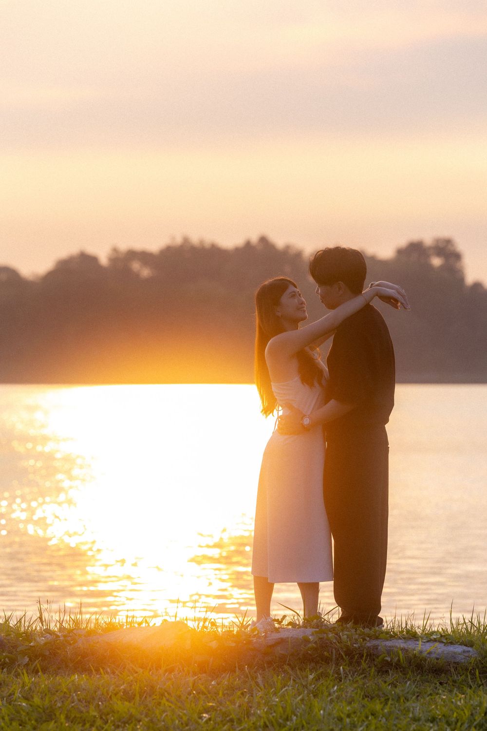 Silhouettes of lovers sharing tender moments against a warm sunset over water.