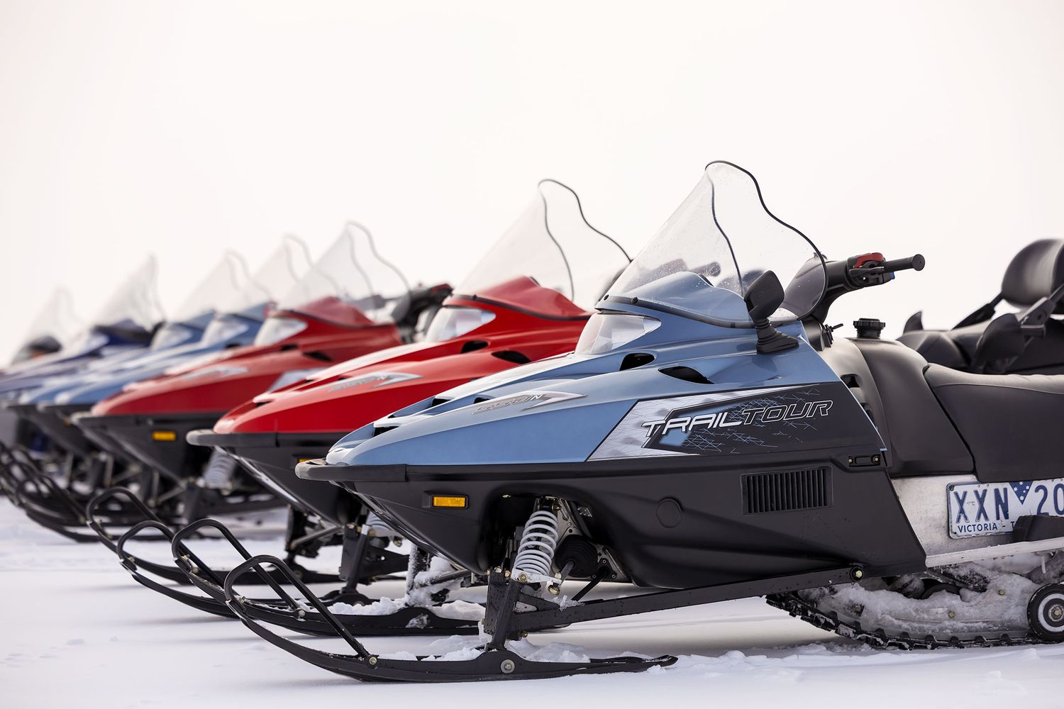 A row of snowmobiles parked in the snow against a bright white winter background at Falls Creek Resort in the Victorian High Country.