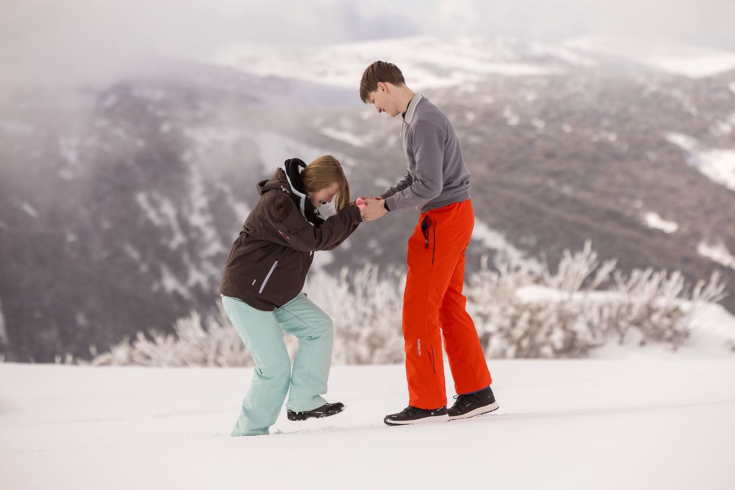 A winter marriage proposal scene with snowy mountain peaks in the background as a couple shares a special moment at Falls Creek Resort.