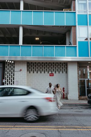 Time-lapse sequence shows car speeding past a modern building entrance with people waiting outside.
