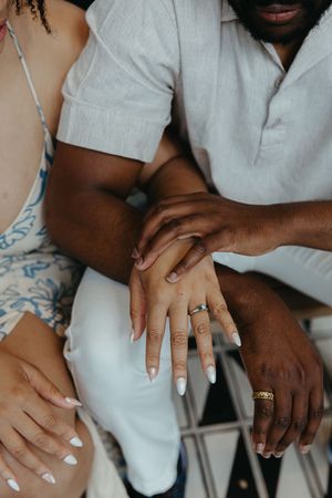 Close-up shot of hands showing matching wedding rings, with one person wearing white and others in lighter colors.