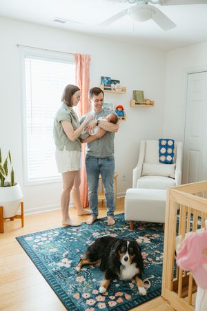 Couple dancing together in a bright living room with hardwood floors and a decorative blue rug.