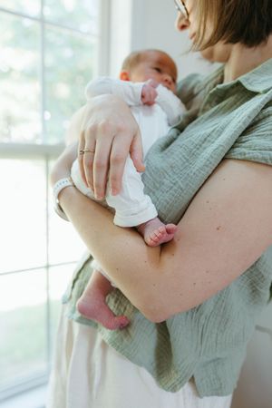 A tender moment between parent and baby, showing delicate hands embracing in soft natural light by a window.