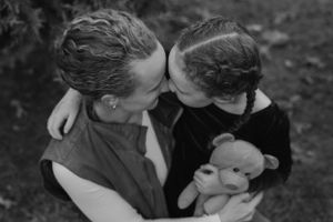 Vintage black and white photo of couple sharing intimate moment while holding stuffed toy.