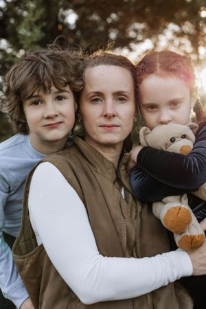 Portrait of family members with stuffed toy against sunset background.