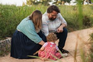 A family kneeling together on a dirt path during a tender outdoor moment.
