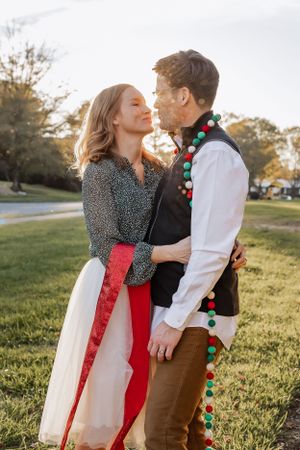 A couple in festive holiday attire share an intimate moment outdoors.