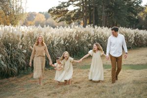 A family walks together through a scenic field with tall pampas grass during golden hour.