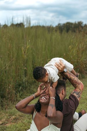 A joyful family moment captured outdoors in a field of tall grass on a cloudy day.
