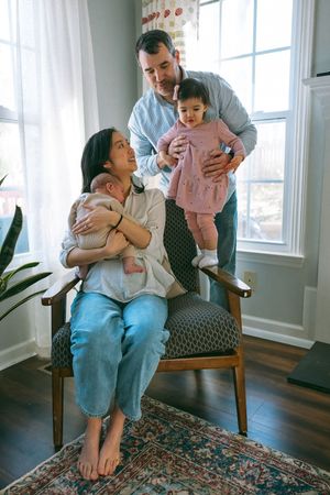 A happy family moment captured at home with parents and children sharing joyful laughter together in a bright living room.