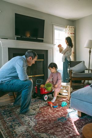 A family spends time together in a cozy living room with a fireplace, TV and decorative rug.