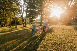 A family walking together in a sunlit park during golden hour creating long shadows.