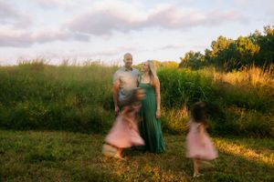 Motion-blurred family photo in a field at sunset with dreamy atmosphere.