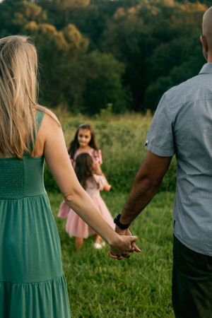 Couple holding hands in a green field during sunset.