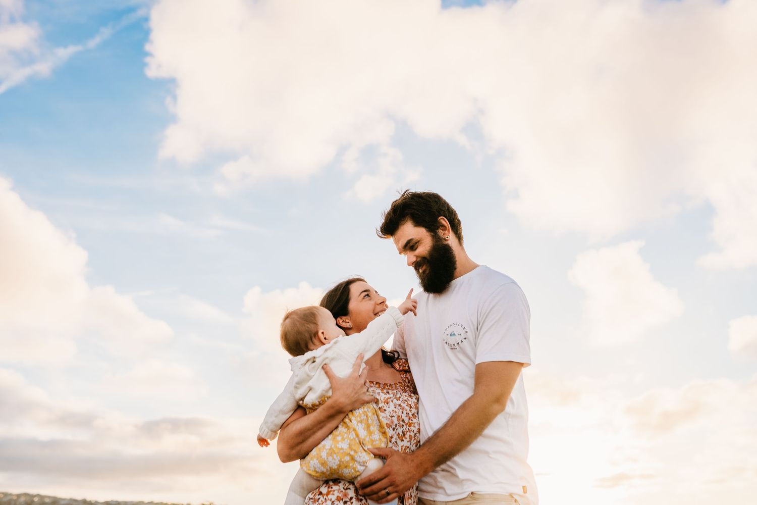 Tender moment between parent and baby against a bright sky background.