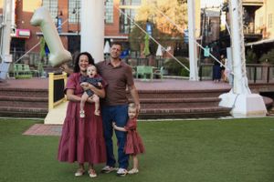Family standing together on artificial turf in front of modern urban architecture.
