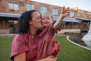 Mother and child sharing joyful moment outdoors on grass.
