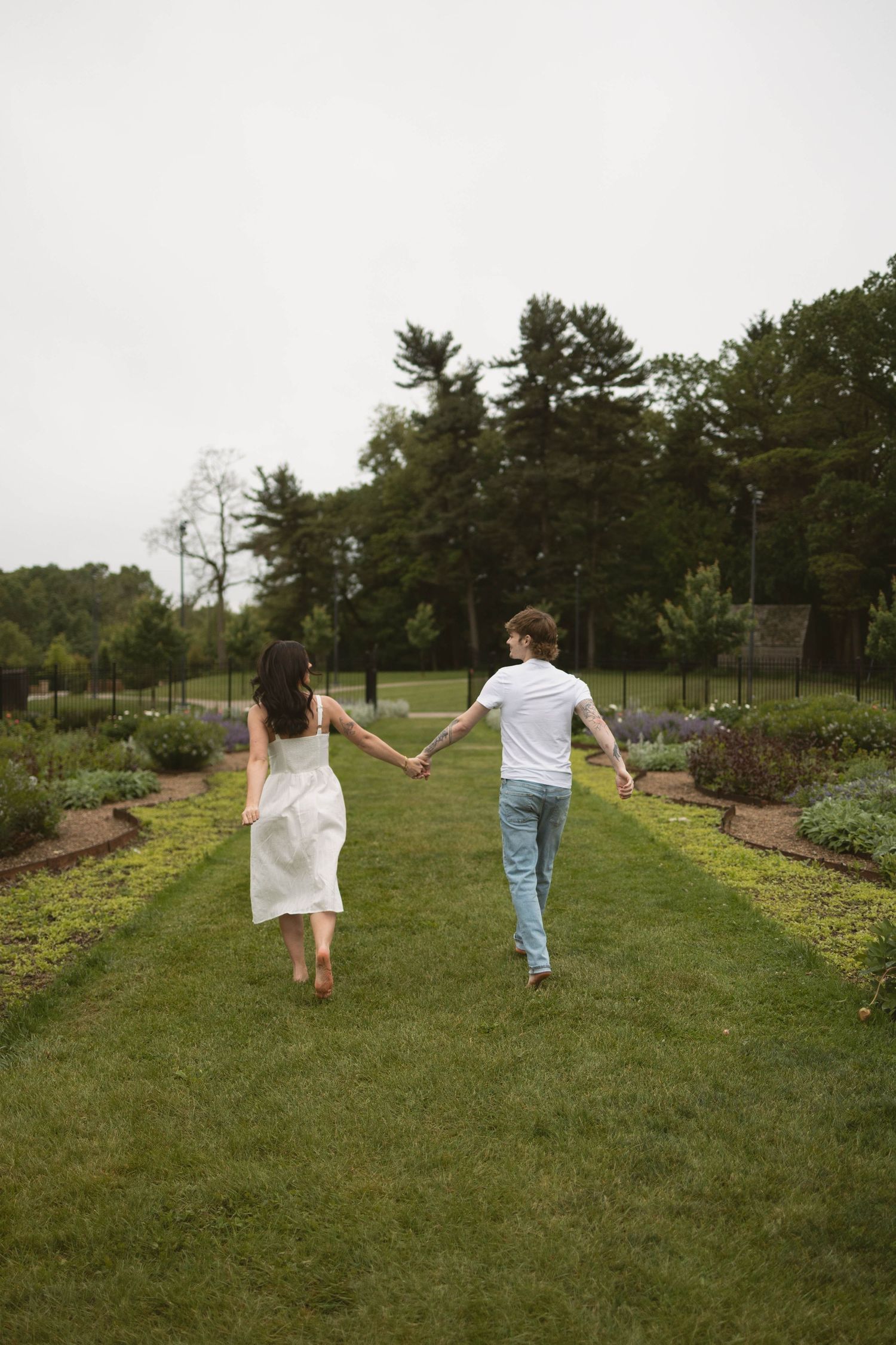 Close-up shot of a couple holding hands while wearing jeans and casual clothing, standing against a blurred background.