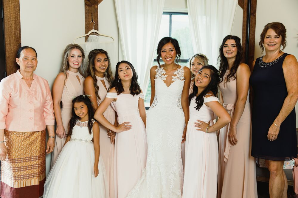 Bridal party lineup in pink and white dresses against rustic interior.