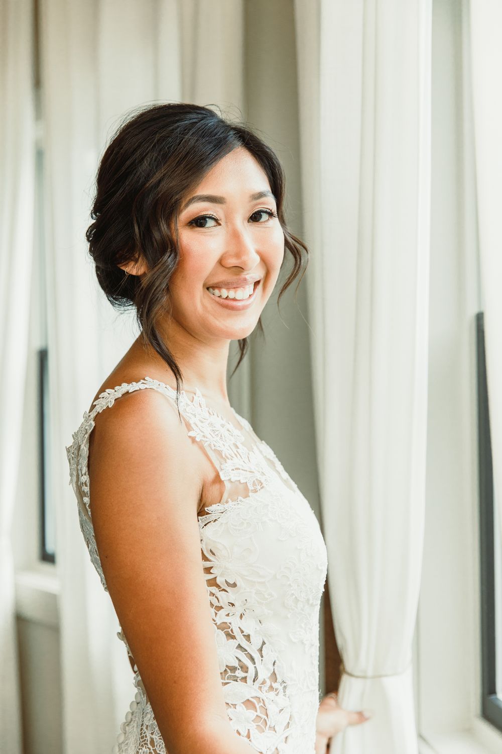Elegant bridal portrait against white curtain backdrop.