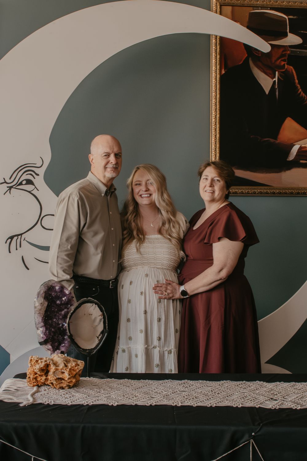 Family of three posing together in front of a decorative moon backdrop at a special celebration event.