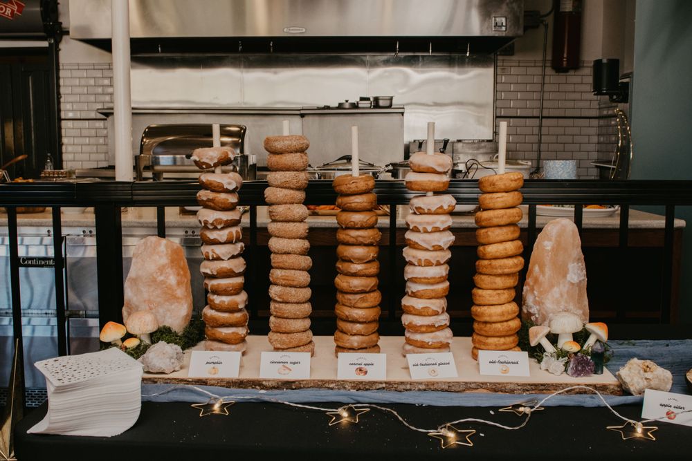 Stacked bagel tower display on black table with labels and floral decorations at baby shower brunch.