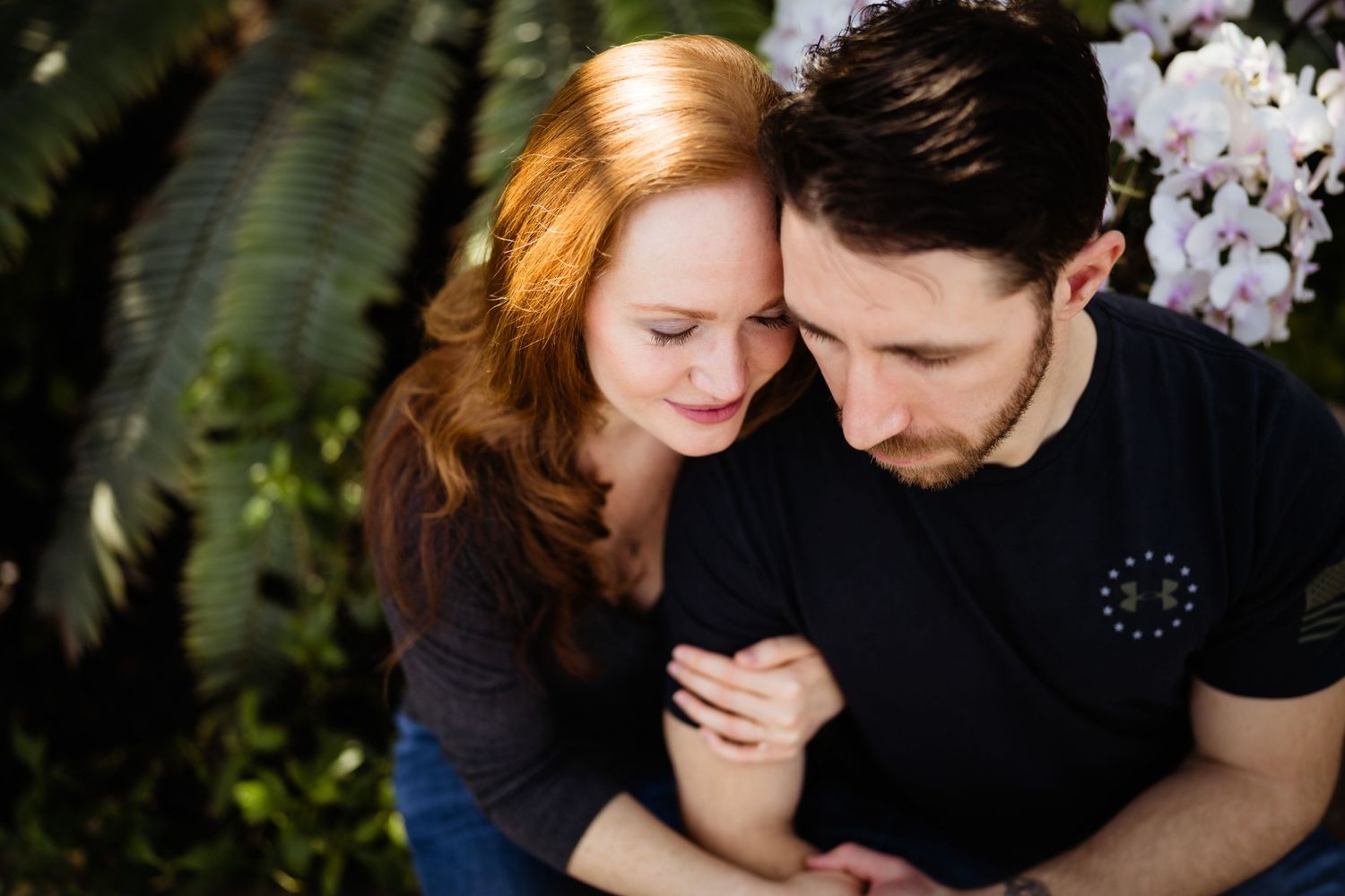 Intimate close-up of couple sharing tender moment among tropical plants.