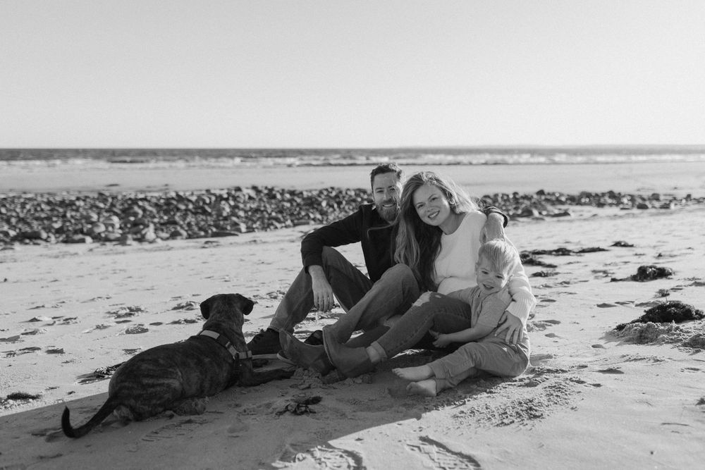 People relaxing on a rocky beach shoreline in black and white.