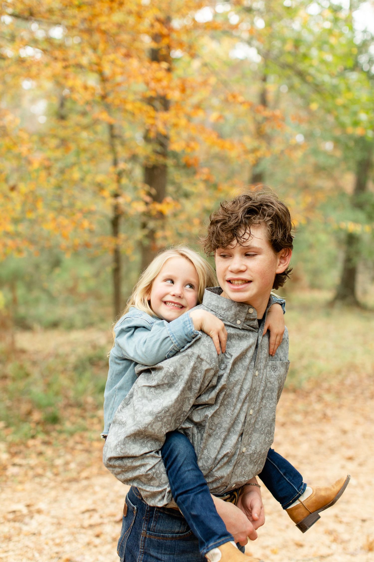 Playful piggyback ride moment captured on an autumn forest trail.