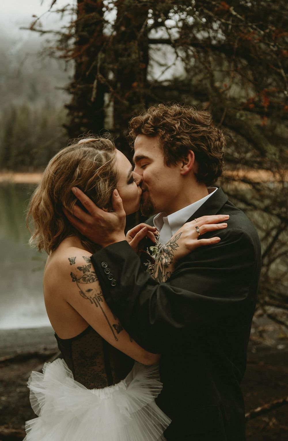 moody elopement photos a couple kissing in a rainy forest in Wisconsin