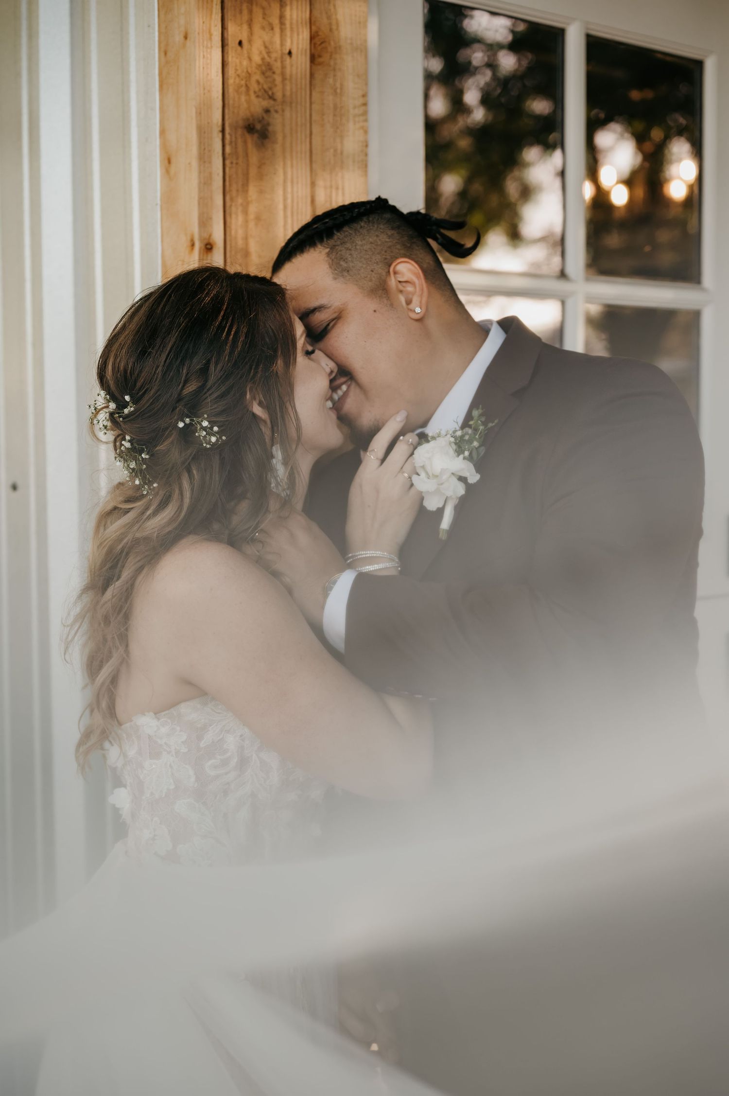 An intimate wedding portrait captured through soft focus and natural window light.